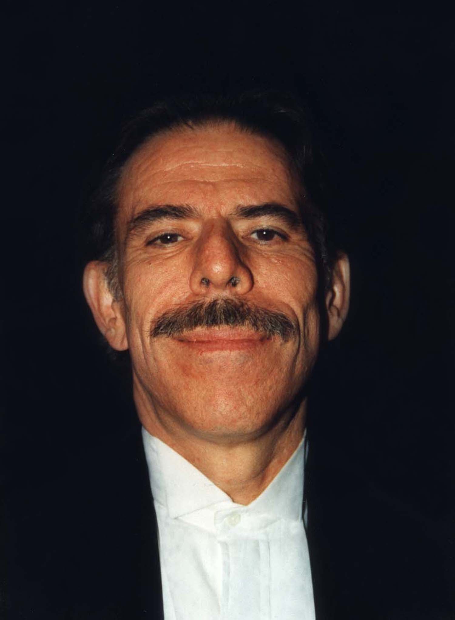 Peter Max smiling in a dark jacket and white shirt, 1998